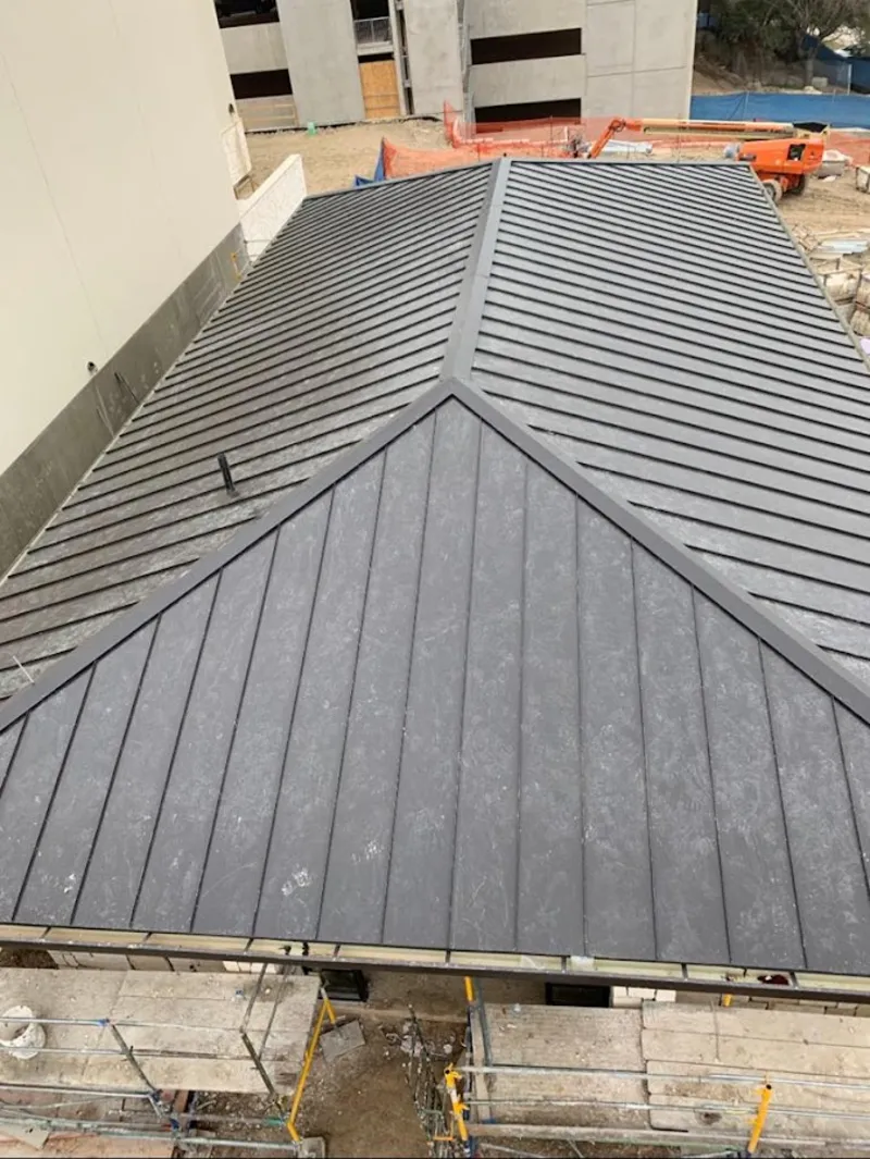 Commercial metal roof construction with crane equipment in Rockwall